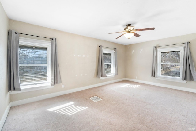 carpeted empty room with a ceiling fan, baseboards, and visible vents