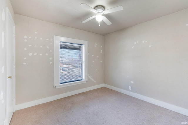 empty room with light colored carpet, baseboards, and ceiling fan