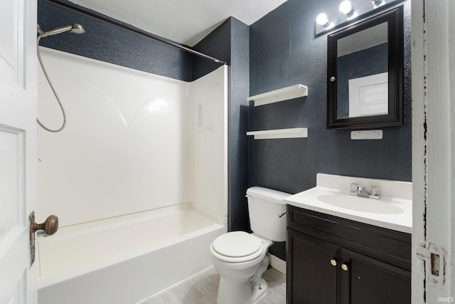 bathroom featuring vanity, washtub / shower combination, toilet, and a textured wall