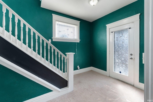 carpeted entryway featuring baseboards and stairs