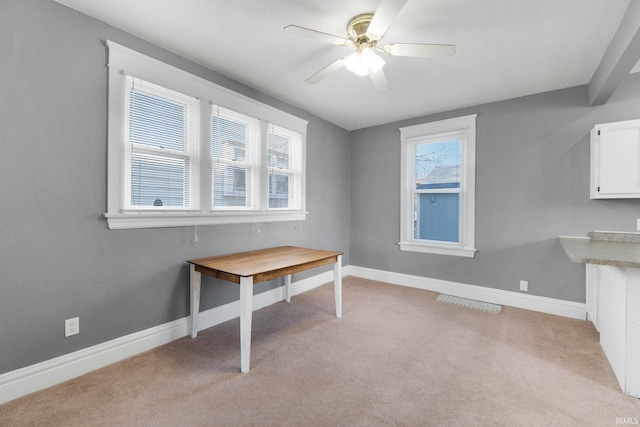 unfurnished office with ceiling fan, baseboards, and light carpet