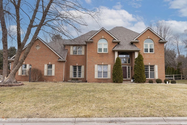 view of front of house with brick siding, a front yard, and a shingled roof