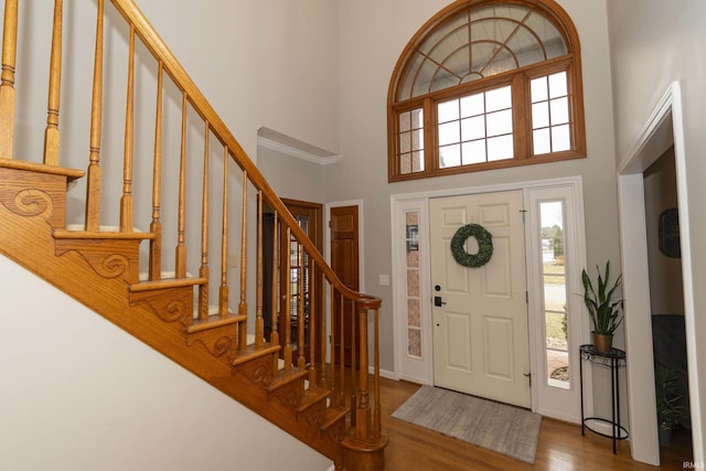 entrance foyer with stairs, wood finished floors, and a towering ceiling