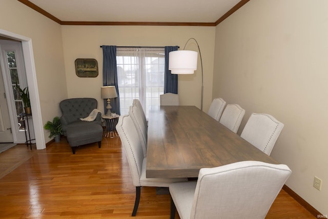 dining space featuring light wood-type flooring, baseboards, and ornamental molding