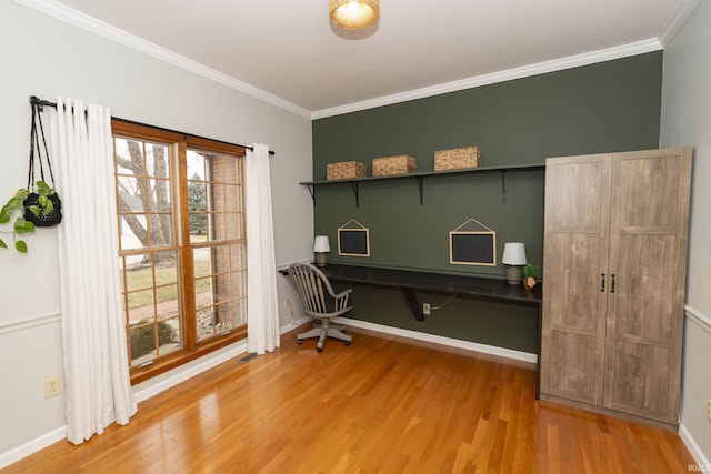 home office with light wood-style flooring, built in study area, crown molding, and baseboards