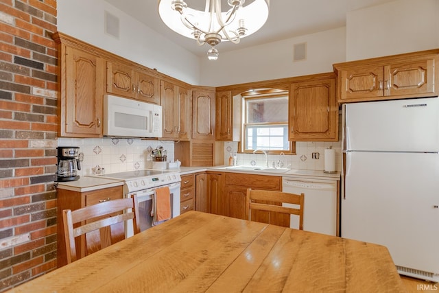 kitchen with a notable chandelier, a sink, white appliances, light countertops, and decorative backsplash