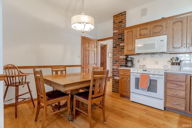 kitchen with tasteful backsplash, visible vents, light wood-style flooring, and white appliances