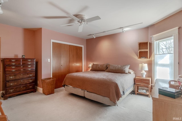 bedroom with a closet, track lighting, a ceiling fan, and carpet