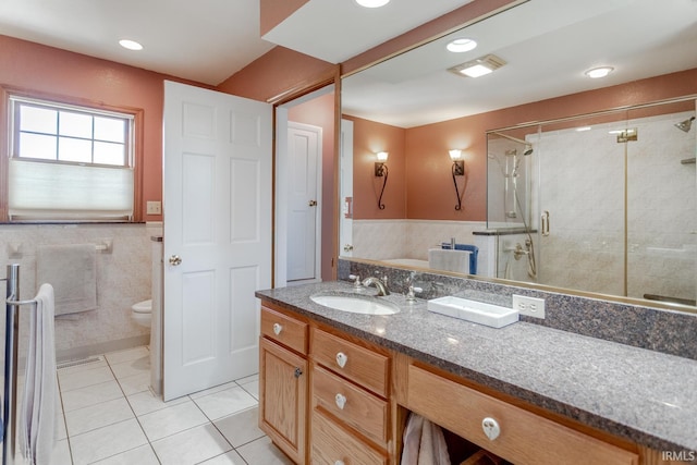 full bathroom featuring vanity, a shower stall, tile walls, toilet, and tile patterned floors