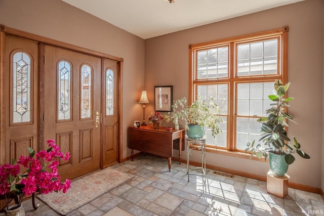 entryway featuring a wealth of natural light, visible vents, baseboards, and stone tile floors