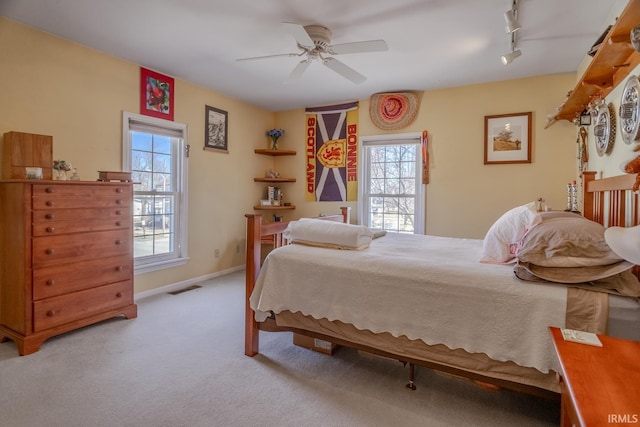 bedroom featuring visible vents, track lighting, a ceiling fan, carpet, and baseboards