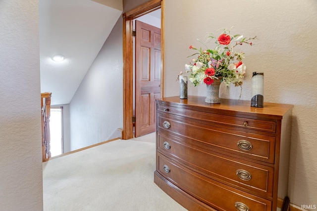 hall featuring light colored carpet and a textured wall