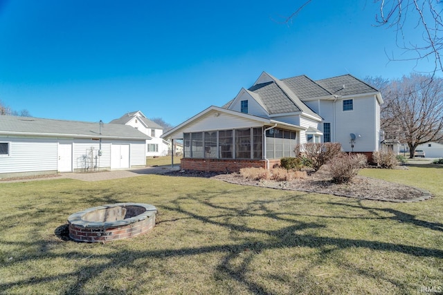 rear view of property with a yard, a fire pit, and a sunroom