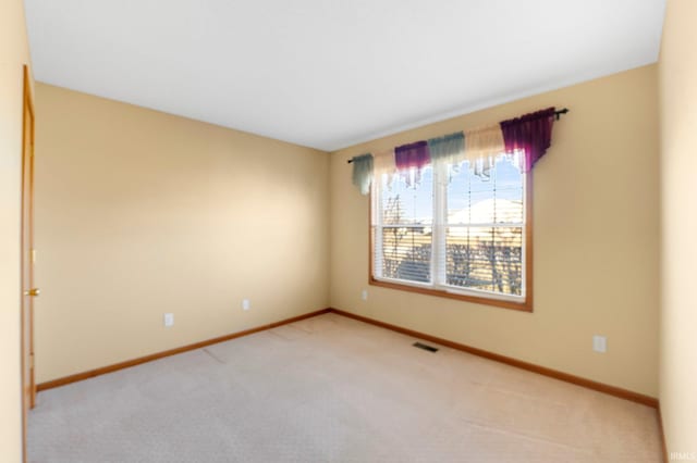 unfurnished room featuring baseboards, visible vents, and light carpet