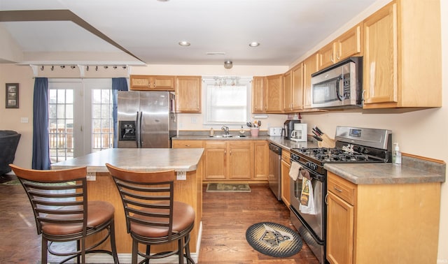 kitchen featuring a wealth of natural light, light brown cabinets, appliances with stainless steel finishes, and a center island