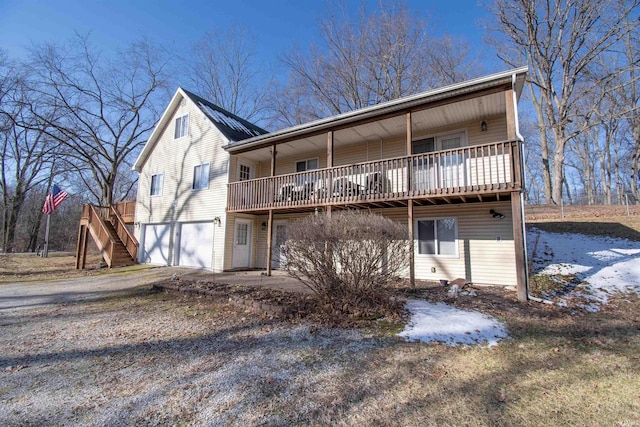 back of property with a garage, driveway, and stairs