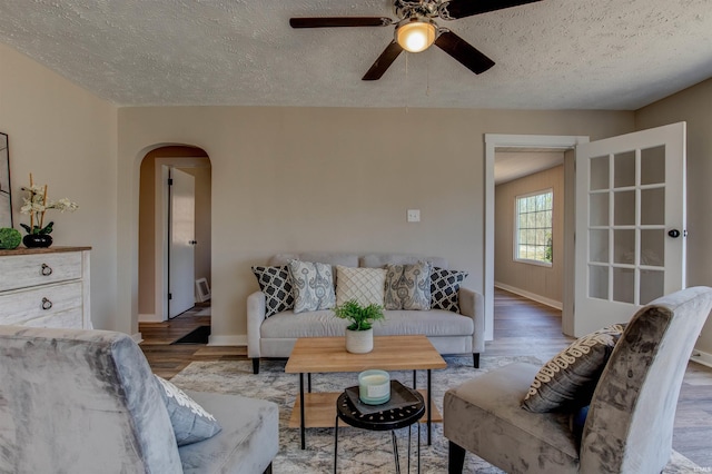 living area featuring arched walkways, a textured ceiling, and wood finished floors