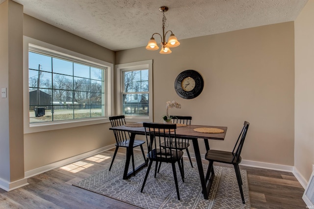 dining space with a chandelier, baseboards, and wood finished floors