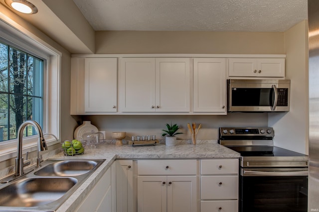 kitchen featuring white cabinetry, stainless steel appliances, light countertops, and a sink