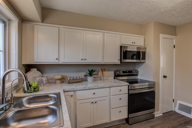 kitchen with visible vents, dark wood-type flooring, a sink, appliances with stainless steel finishes, and light countertops