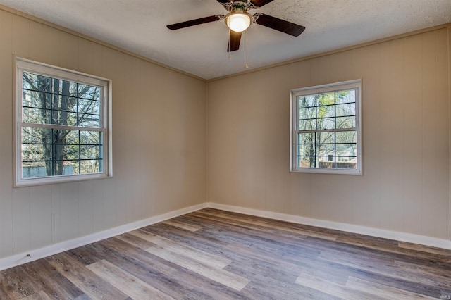 unfurnished room with ceiling fan, baseboards, a textured ceiling, and wood finished floors