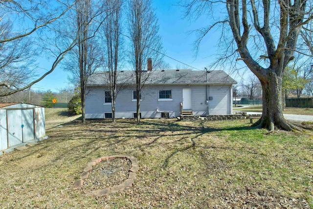 rear view of property featuring a lawn, entry steps, a storage shed, an outdoor structure, and a chimney