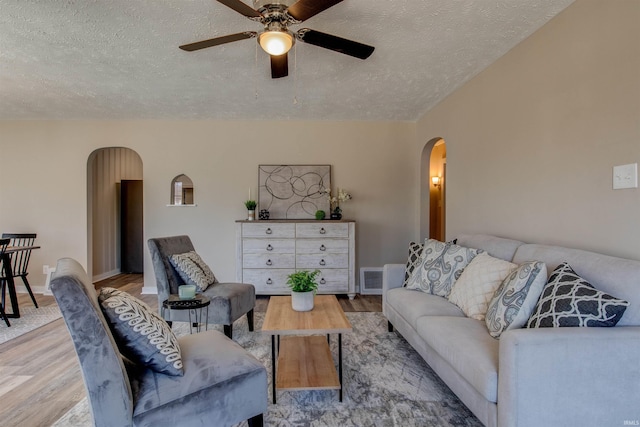 living area featuring visible vents, wood finished floors, arched walkways, and a textured ceiling