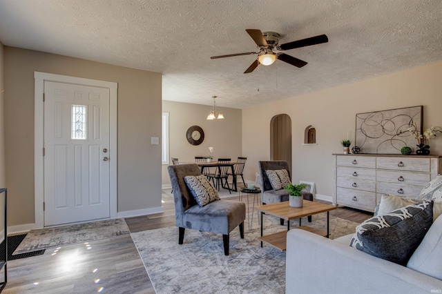 living area featuring baseboards, wood finished floors, arched walkways, and a textured ceiling