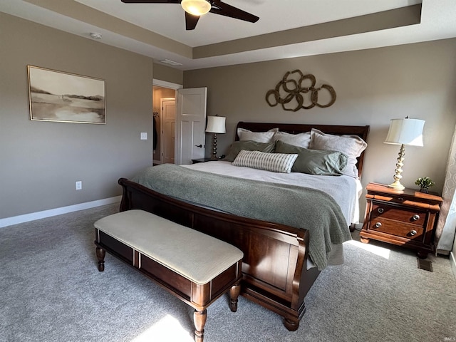 bedroom featuring a raised ceiling, a ceiling fan, baseboards, and carpet floors