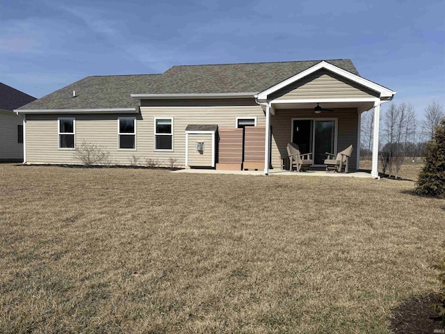 back of property with a lawn, roof with shingles, and ceiling fan