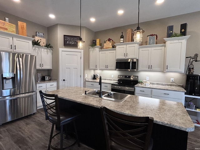 kitchen with a kitchen bar, appliances with stainless steel finishes, dark wood finished floors, and white cabinetry