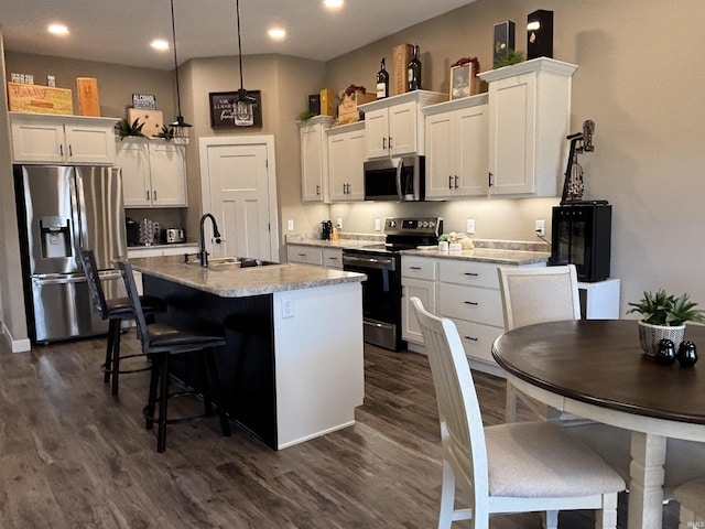 kitchen featuring a sink, appliances with stainless steel finishes, white cabinets, and a center island with sink