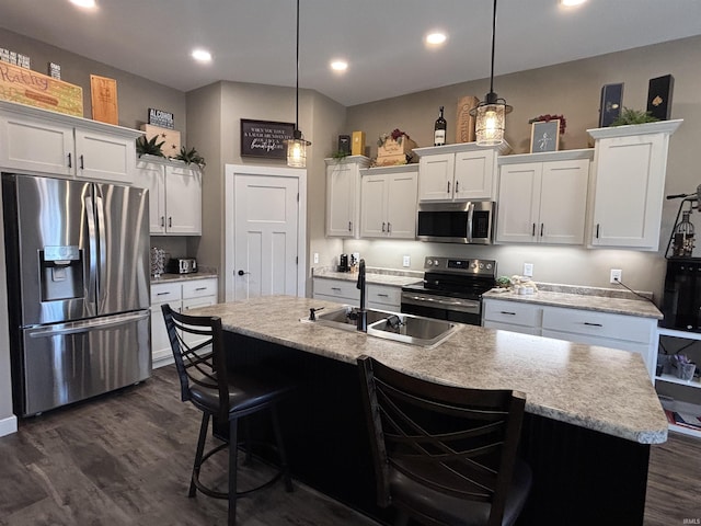 kitchen with dark wood finished floors, white cabinets, appliances with stainless steel finishes, and a sink