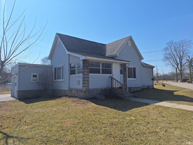 view of front of home with entry steps, a front lawn, and a shingled roof