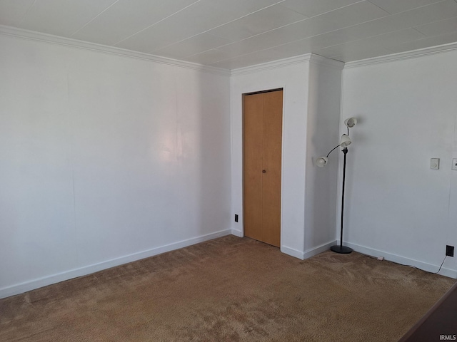 empty room featuring carpet flooring, baseboards, and crown molding