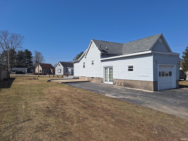 view of home's exterior featuring a lawn, french doors, a shingled roof, a garage, and a patio area