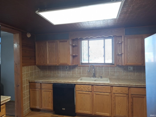 kitchen featuring tile counters, black dishwasher, open shelves, and a sink