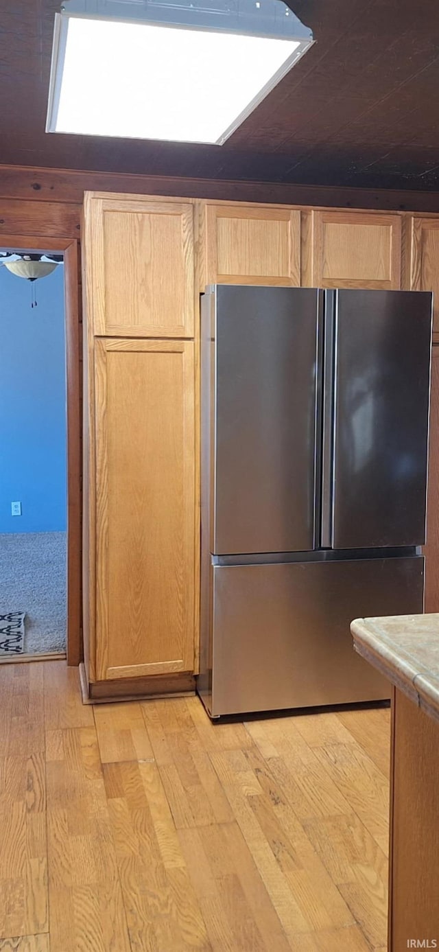 kitchen featuring light wood-type flooring, light brown cabinets, and freestanding refrigerator