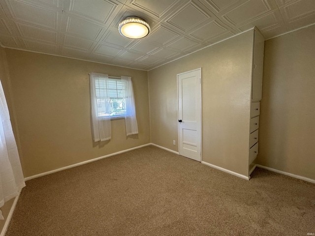 unfurnished bedroom with baseboards, an ornate ceiling, and carpet floors