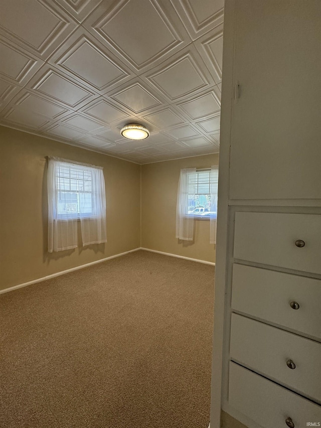 carpeted spare room with baseboards and an ornate ceiling