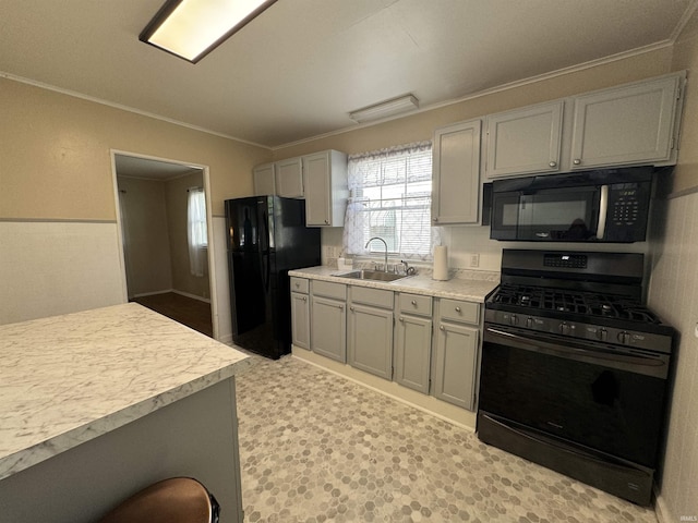 kitchen featuring a sink, black appliances, ornamental molding, and light countertops