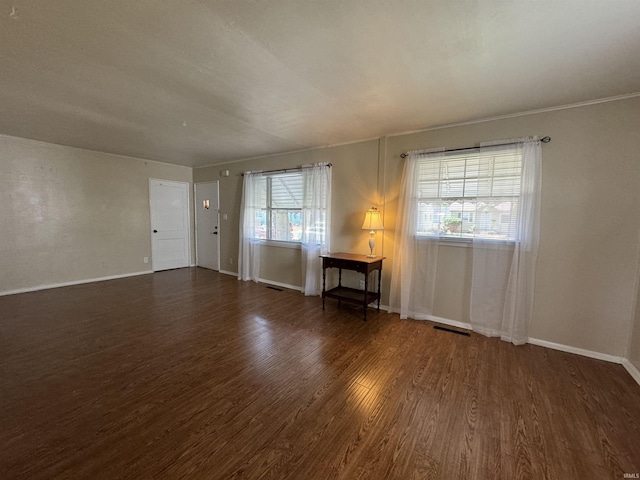 empty room featuring visible vents, baseboards, and wood finished floors