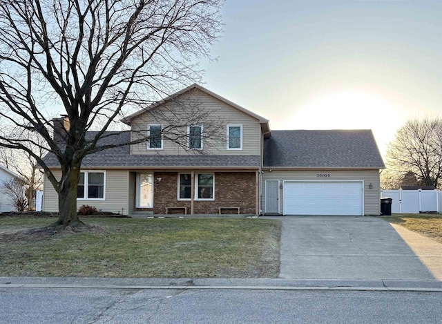 traditional home featuring brick siding, a front lawn, fence, concrete driveway, and a garage