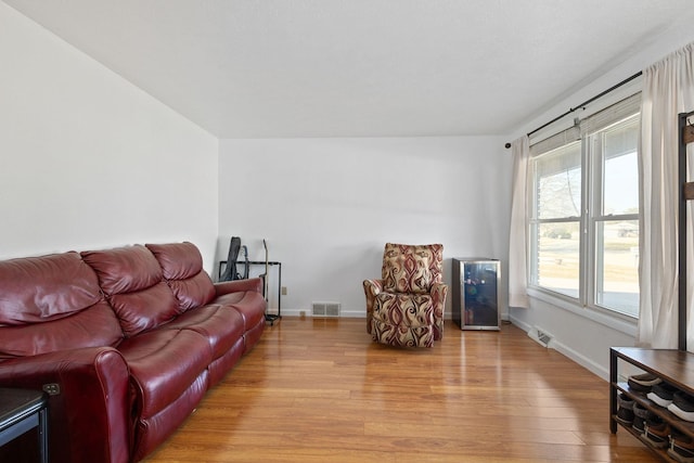 living room with visible vents, baseboards, and light wood-style floors