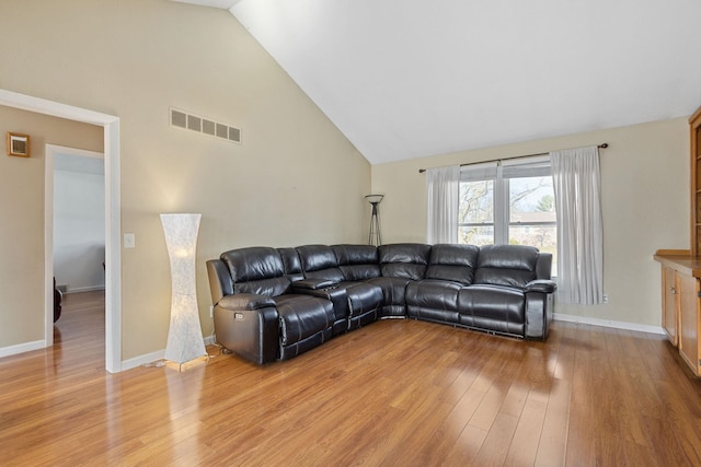 living area featuring baseboards, visible vents, light wood finished floors, and high vaulted ceiling