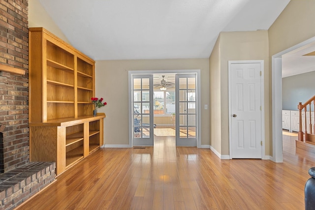 unfurnished living room featuring stairway, a brick fireplace, baseboards, and hardwood / wood-style flooring