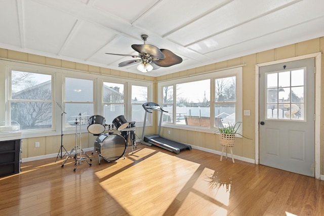 workout area featuring light wood-style flooring, a ceiling fan, and baseboards