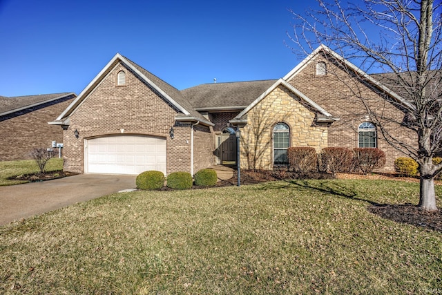 view of front facade featuring driveway, stone siding, a front yard, a garage, and brick siding