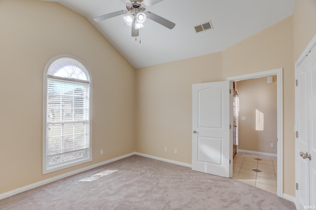 tiled spare room featuring visible vents, baseboards, carpet, vaulted ceiling, and a ceiling fan