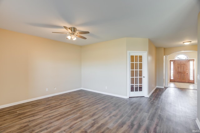 empty room with a ceiling fan, baseboards, and dark wood-style flooring